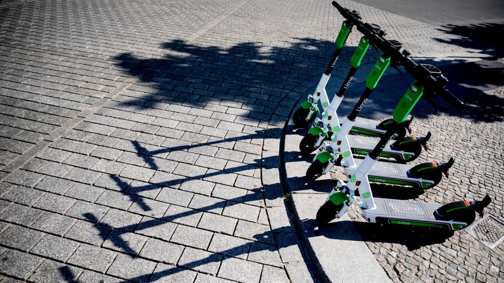 Vier grün-weiße E-Roller auf Kopfsteinpflaster