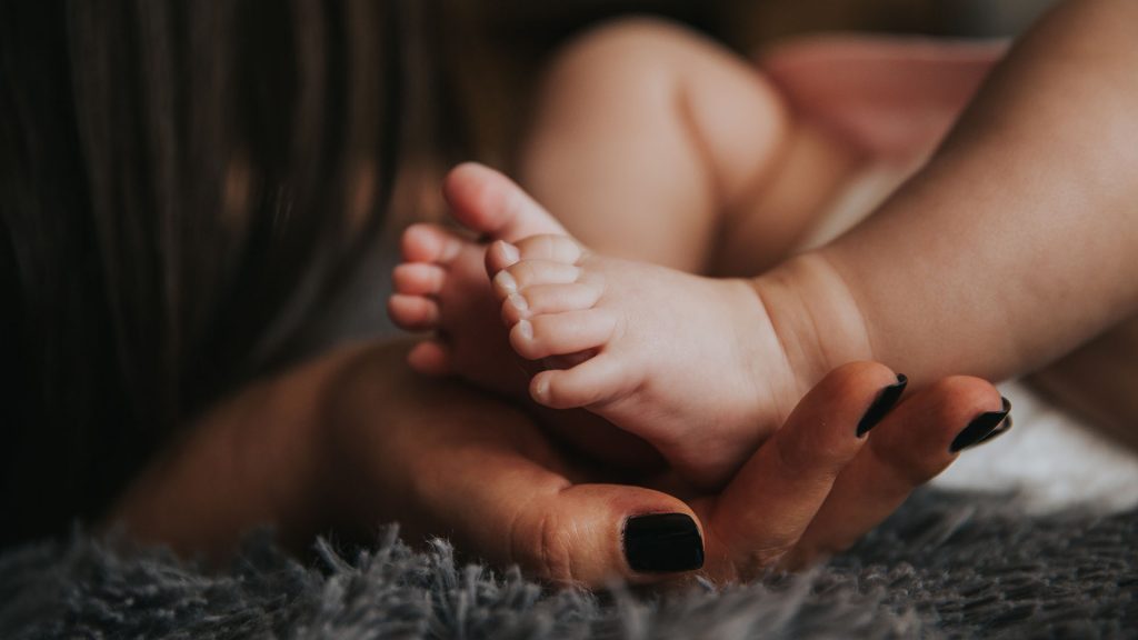 Hand umfasst nackte Babyfüße