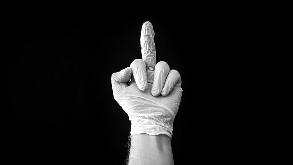 Mittelfinger in Gummihandschuhen vor schwarzem Hintergrund.
