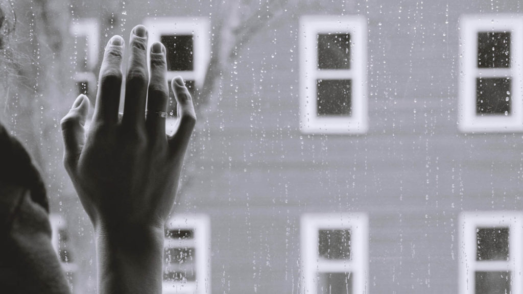 Frau steht am Fenster und schaut hinaus