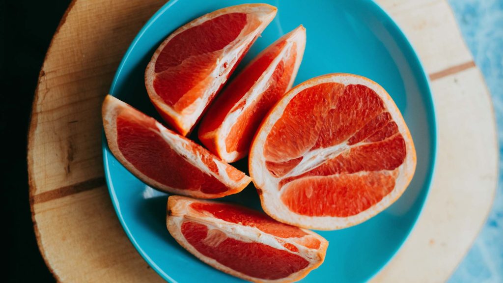 Grapefruit aufgeschnitten auf blauem Teller.