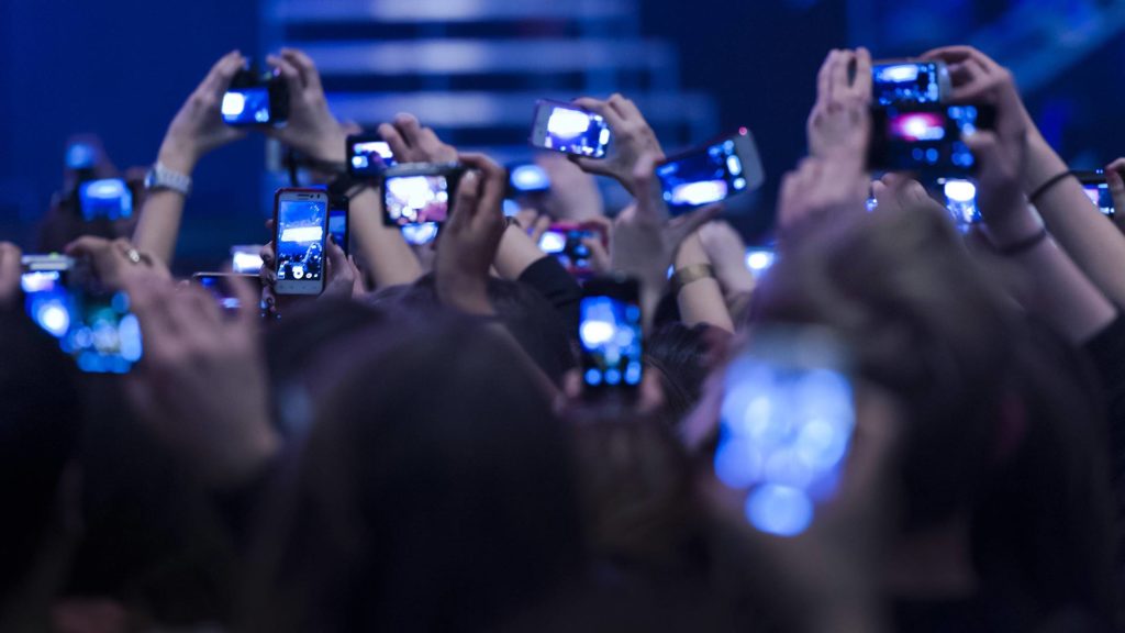 Jugendliche Fans halten Fotohandys bei einem Konzert in die Höhe.