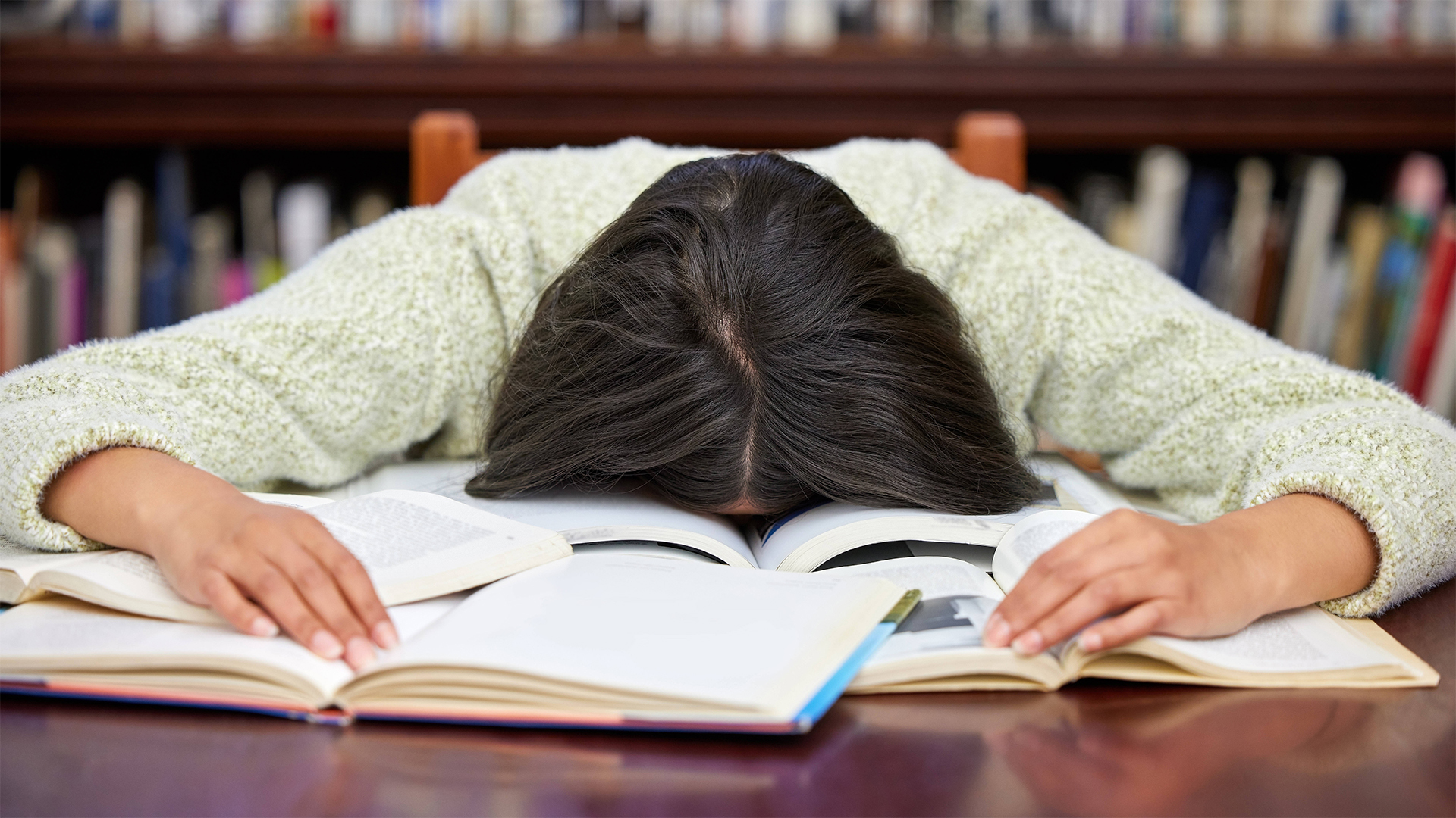 Eine junge Frau liegt erschöpft auf einem Buch.