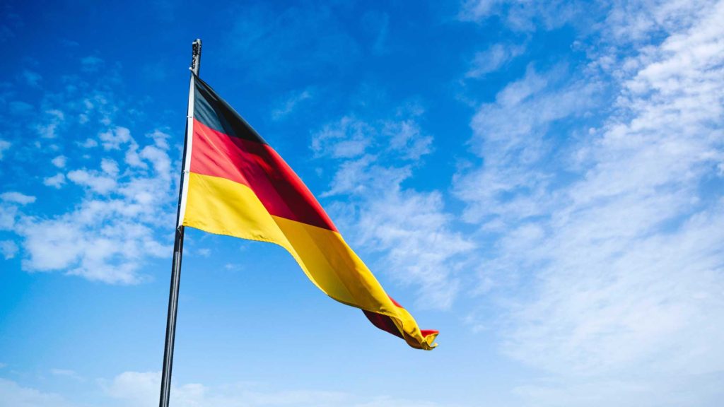 Deutsche Flagge vor Wolkenhimmel.