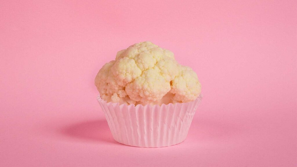 Blumenkohl in einem Muffinförmchen auf einer pinken Fläche.