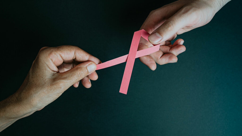 Zwei Personen halten eine pinke Schleife, um auf Brustkrebs aufmerksam zu machen.