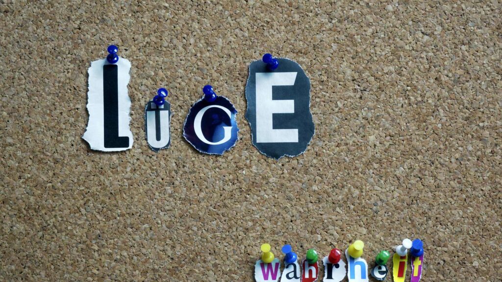 Die Wörter "Lüge" und "wahr" sind mit Stecknadeln an eine Pinnwand aus Kork geheftet worden.