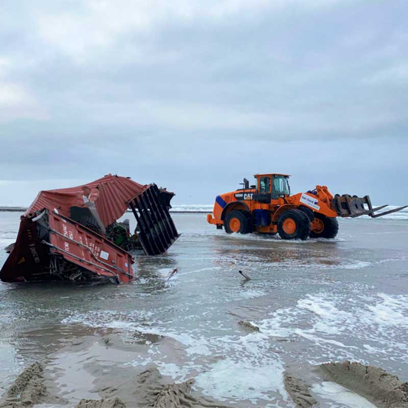 Die Trümmer von Frachtcontainern werden von einem Strand entfernt.