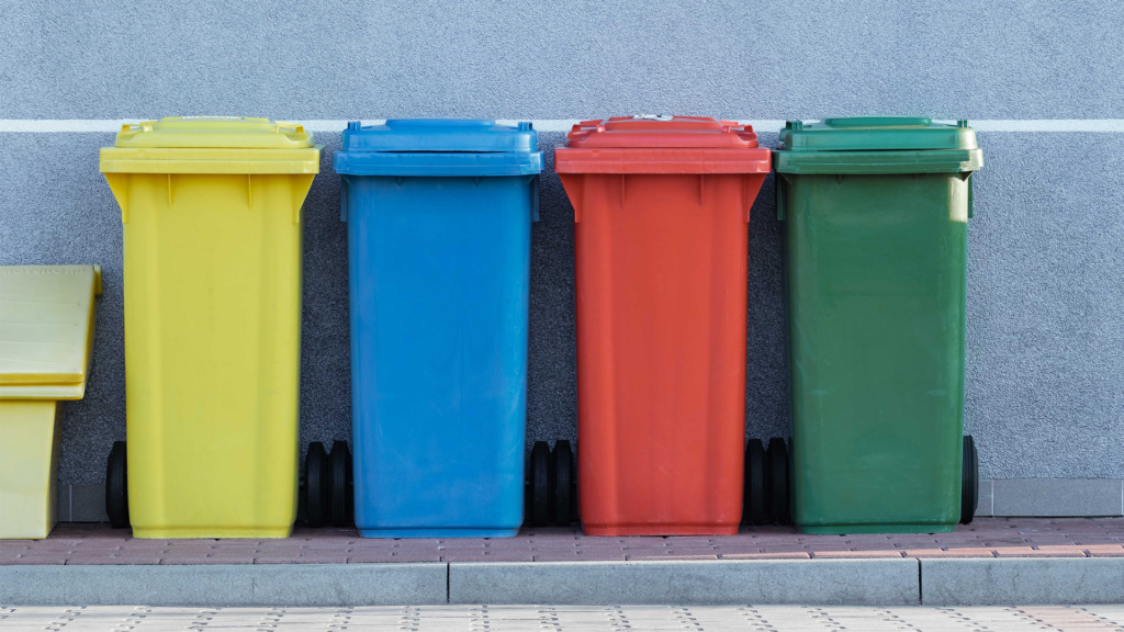 Vier Mülltonnen unterschiedlicher Farbe nebeneinander.