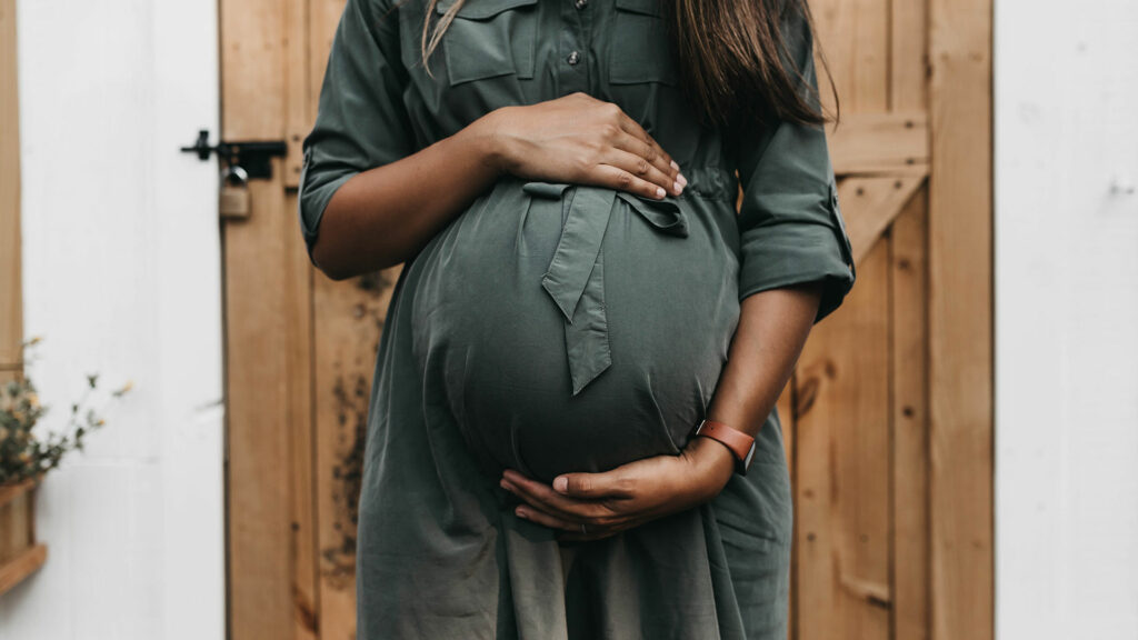 Eine schwangere Frau hält ihren Bauch.
