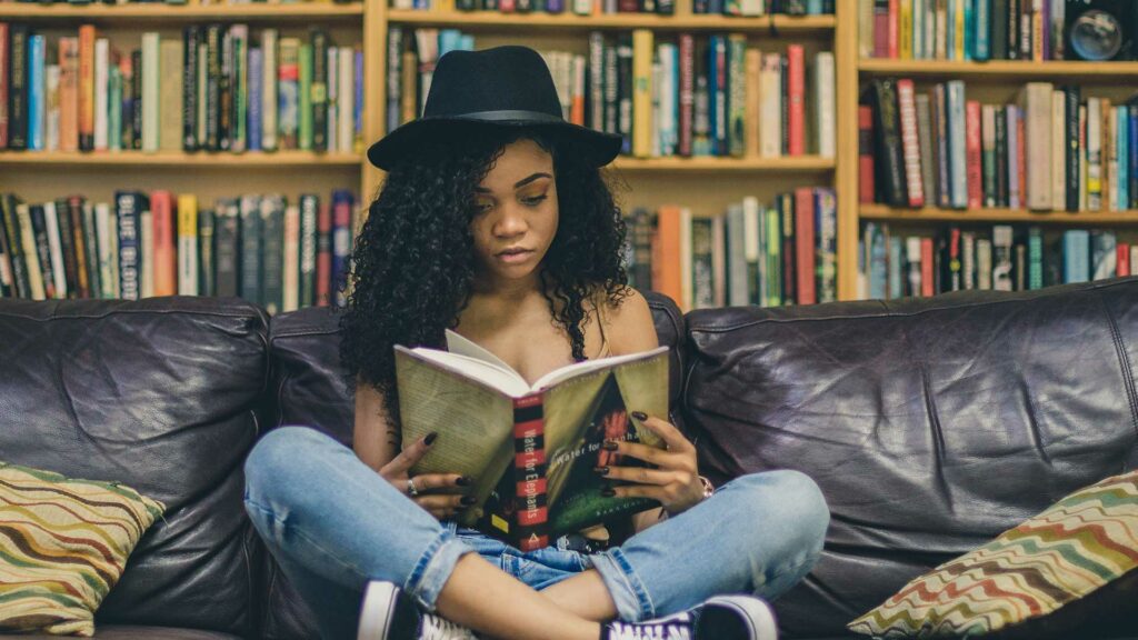 Eine Frau liest ein Buch auf einer Couch.