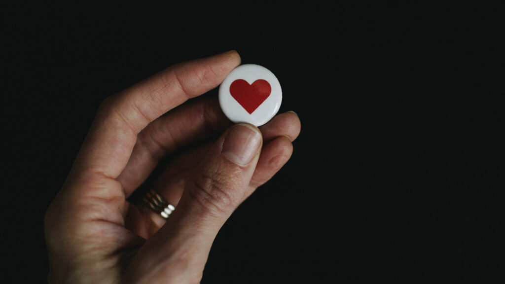 In einer Hand hält eine Person ein Herz-Symbol.