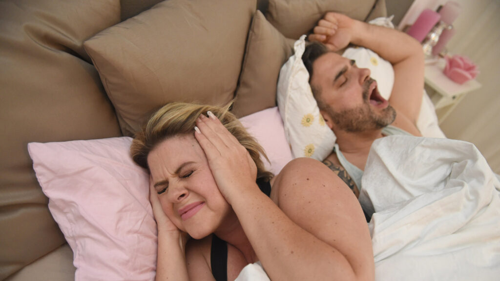 Mann liegt schnarchend im Bett