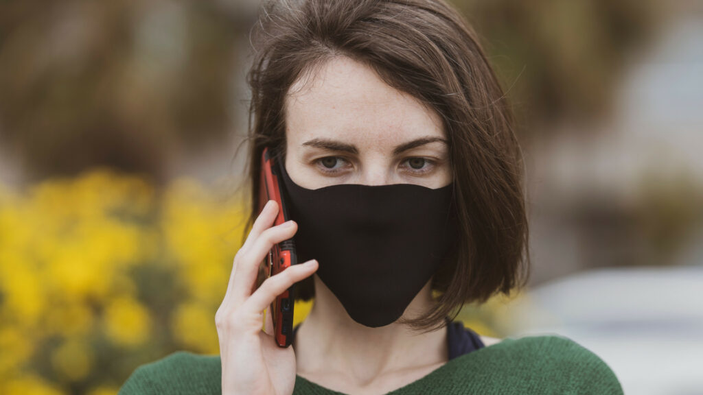 Frau telefoniert mit Maske
