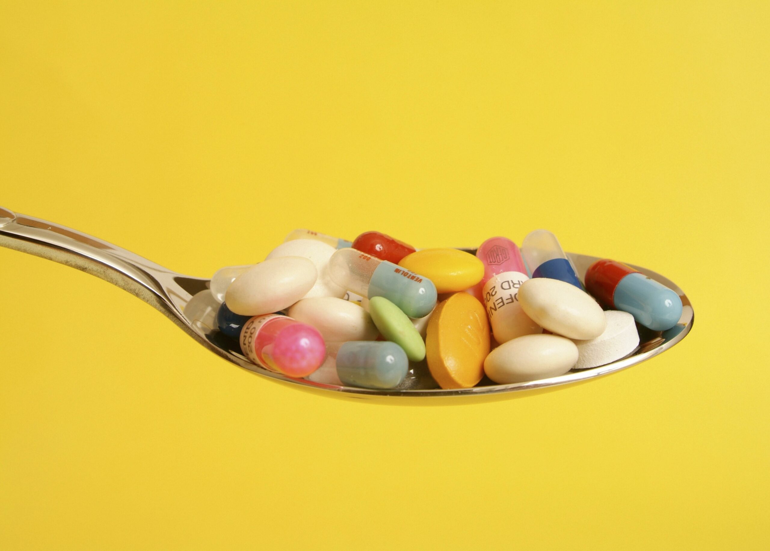 Tabletten am Löffel Löffel mit Nahrungsergänzungsmitteln