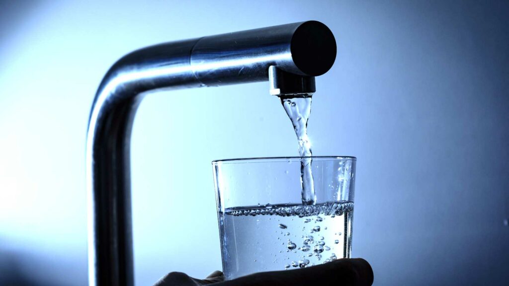 Glas wird mit Wasser aus dem Wasserhahn aufgefüllt.