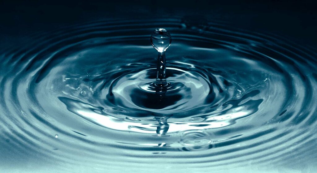 Nahaufnahme eines Wassertropfen, der ins Wasser fällt
