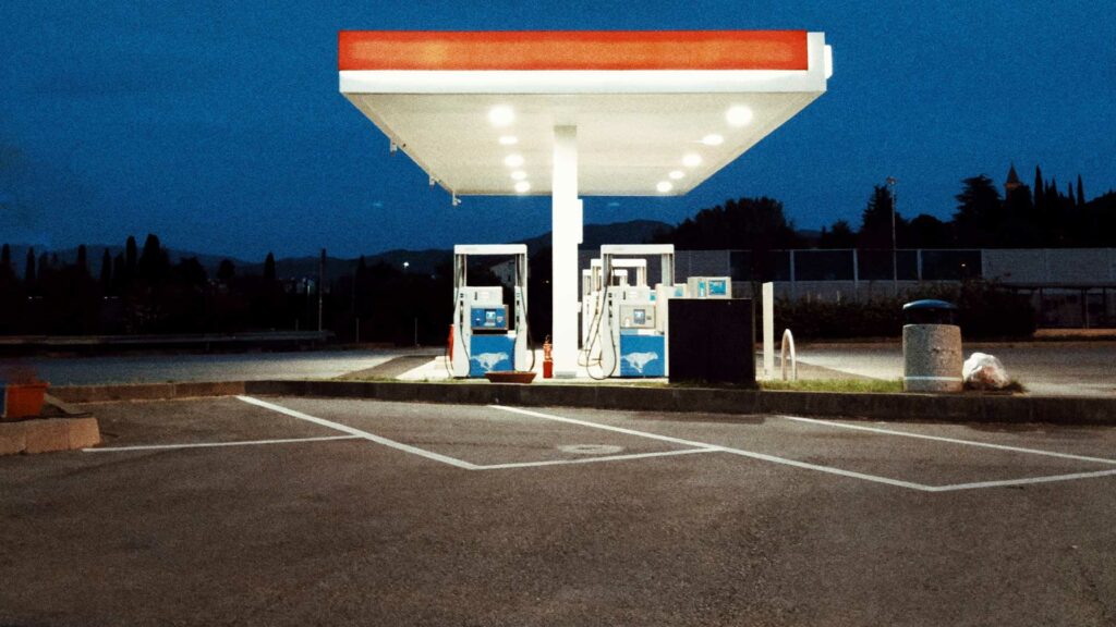 Eine Tankstelle am späten Abend. Es sind keine Menschen zu sehen. Die Tankstelle ist hell beleuchtet.
