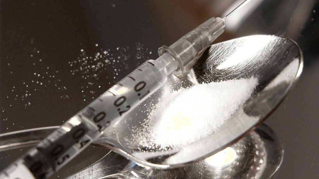 Spritze auf Löffel mit Heroin-Pulver.