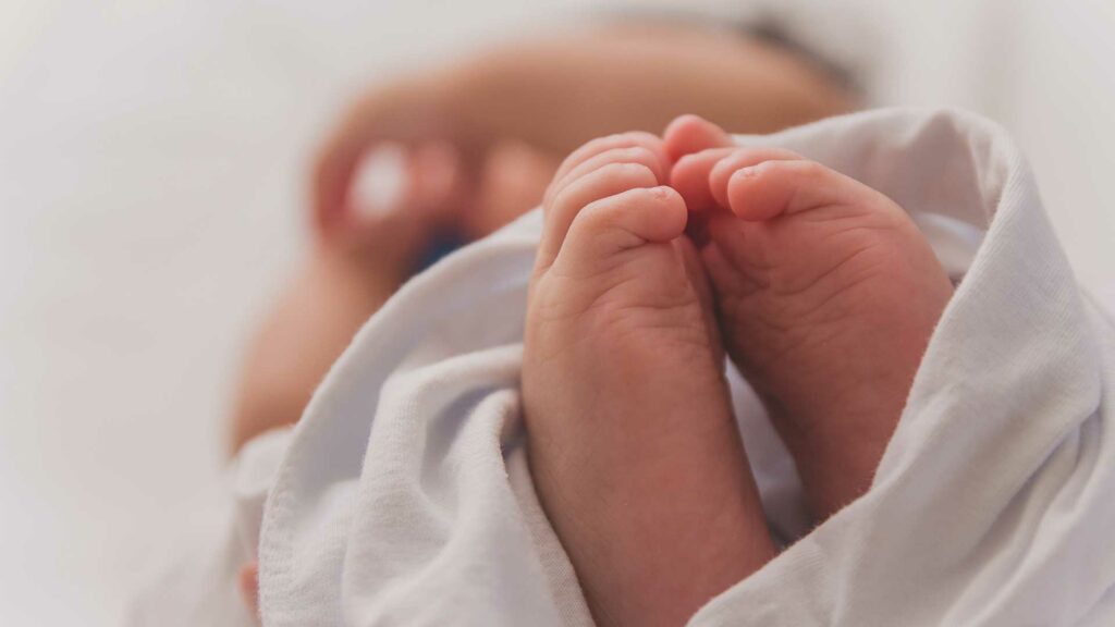 Zwei Füße eines Babys, eingwickelt in eine Decke.