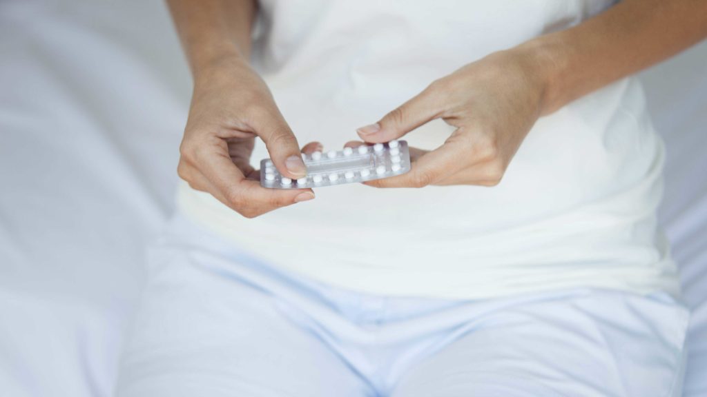Frauenhände halten einen Anti-Babypillen Blister