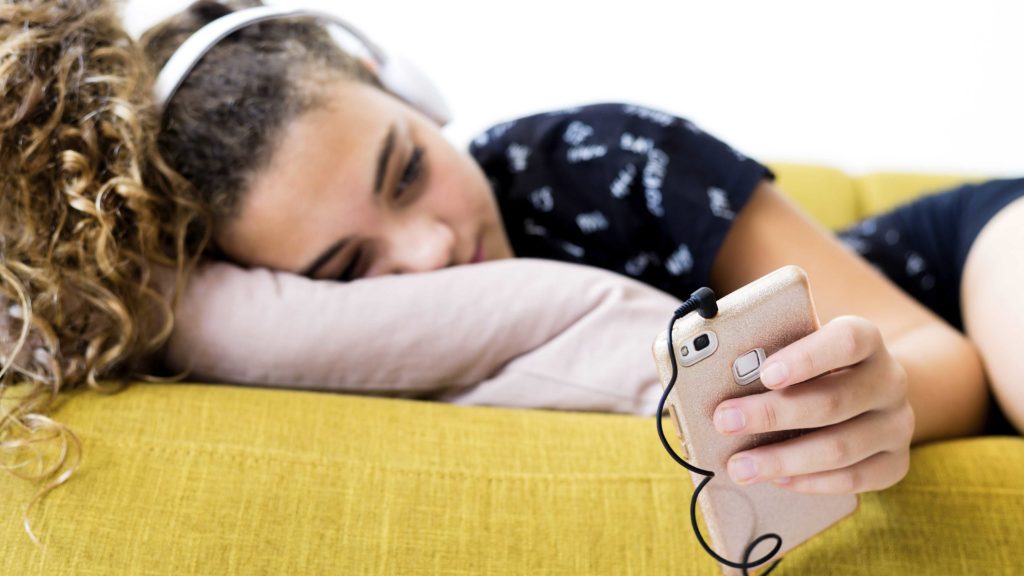 Mädchen liegt auf der Couch und hört Musik